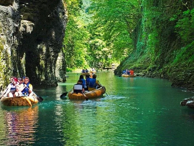 People paddling in inflatable boats along a green river through Martvili Canyon