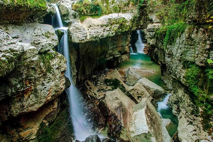 Une cascade s'écoule à travers un canyon rocheux aux vasques vertes