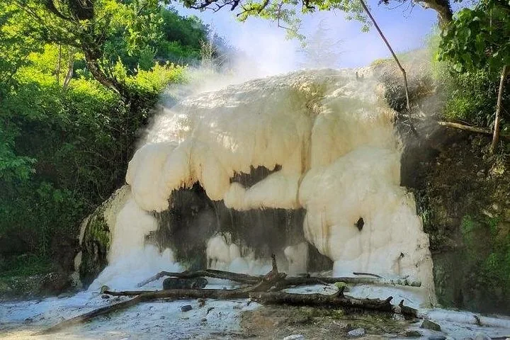 Une formation de source minérale blanche avec de l'eau qui s'écoule et de la vapeur qui s'élève