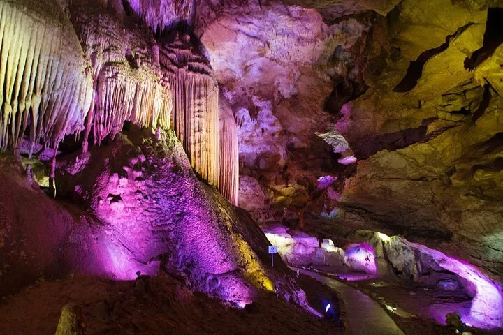 Interno della Grotta di Prometeo illuminato da luci viola e gialle sulle stalattiti